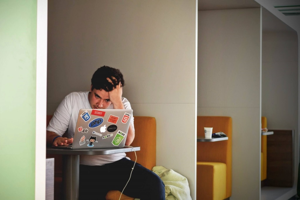 A man sitting behind his laptop and resting his head on his hand.