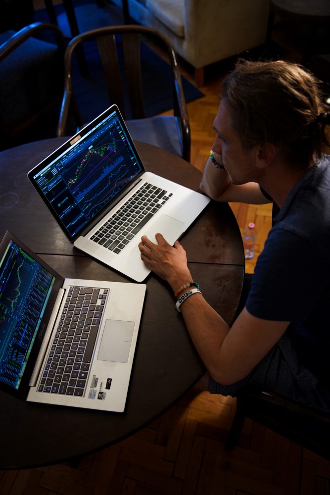 A man sitting in front of two laptops that are showing some type of data.