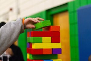 a child stacking wooden toy bricks in different colors